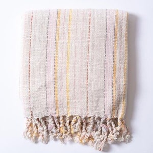 May include: A white throw blanket with thin yellow, pink, and red stripes and a fringe border.