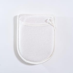 Op de afbeelding: Witte badhandschoen van badstof met een lus om op te hangen. De handschoen is ontworpen om de huid te exfoli&euml;ren en te reinigen.