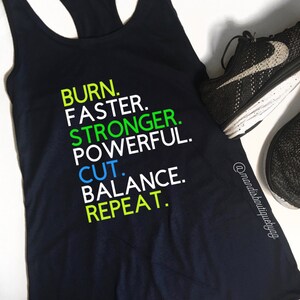 May include: Black tank top with the text "BURN. FASTER. STRONGER. POWERFUL. CUT. BALANCE. REPEAT." in green, blue, and white text.