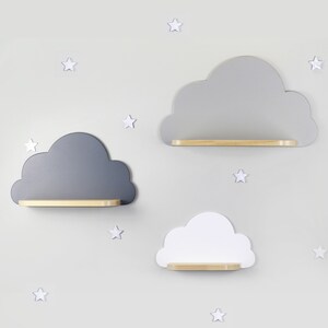 May include: Three cloud-shaped shelves in gray, white, and light gray with wooden shelves. The shelves are mounted on a light gray wall with white stars.