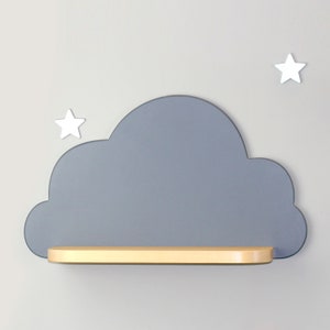 May include: A gray cloud-shaped shelf with a light wood shelf. The shelf is mounted on a gray wall with two white stars on either side.