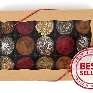 May include: A box of assorted chocolate truffles in a clear plastic container. The box is brown and has a red ribbon tied around it. The box is labeled "Delicious Indecisions" and "Best Seller".