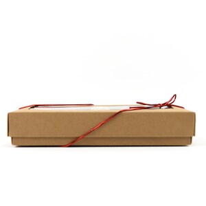 May include: A brown cardboard box with a red ribbon tied around it. The box has a clear window on the top.