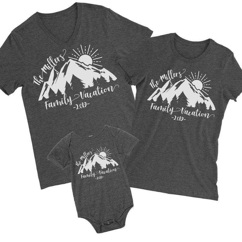 May include: Three gray t-shirts with a white mountain design and the text "The Millers Family Vacation -2019-". The shirts are in different sizes, one for an adult, one for a child, and one for a baby.