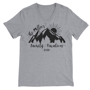 May include: Gray V-neck t-shirt with a black mountain silhouette design. The text "The Millers Family Vacation -2019- " is printed below the mountains.