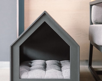 May include: A black wooden dog bed shaped like a house with a gray cushion inside.