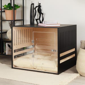 May include: A contemporary dog crate with a black frame and a natural wood interior. It has a clear acrylic door and a cream-coloured cushion. The design incorporates vertical and horizontal slats for ventilation, offering a stylish and modern aesthetic. The crate is designed for indoor use.