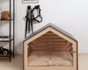 May include: A modern dog house with a house-shaped design. The dog house has a light wood frame, a dark gray roof, and a clear glass door. Inside is a beige cushion. A black leash and harness hang on the wall.