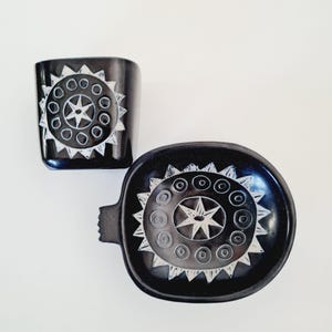 Peut inclure: Ensemble en céramique noire composé d'une tasse carrée et d'un plat rond avec une poignée. Les deux pièces présentent un motif d'étoile blanche gravé dans la céramique noire.
