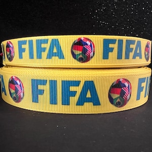 Puede incluir: Dos rollos de cinta amarilla con la palabra "FIFA" impresa en azul y un balón de fútbol con banderas impresas en él.