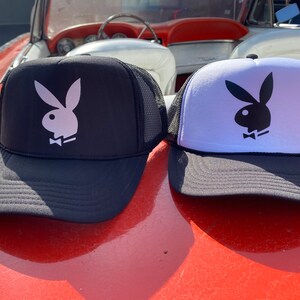 Peut inclure: Deux casquettes de camionneur avec un logo de lapin noir et blanc. Les casquettes sont noires et blanches avec un dos en mesh.