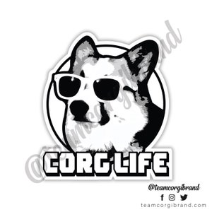 May include: Black and white illustration of a corgi wearing sunglasses with the text "Corg Life" below. The text "@teamcorgibrand" is at the bottom of the image with social media icons.