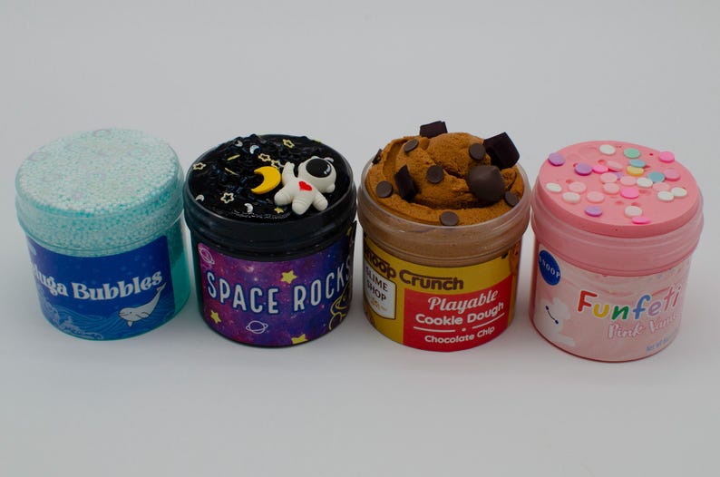May include: Four colorful slime containers. One is light blue with "Lava Bubbles" text, another is black with a space theme and "Space Rocks" text, the third is brown with "Playable Cookie Dough" text, and the last is pink with "Funfeti" text.