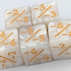 May include: Five ivory-colored dice with gold-colored markings. Each die features a fraction with negative numbers. The dice have a marbled appearance, and the numbers are clearly visible.