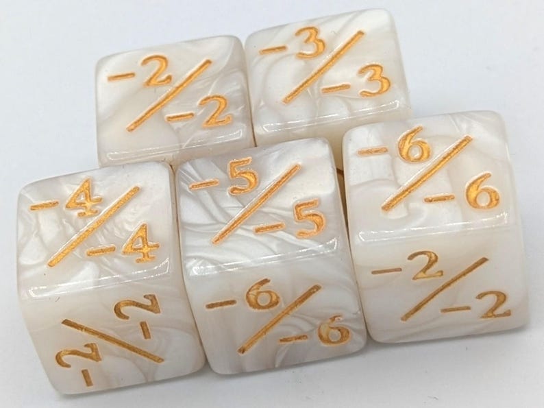 May include: Five ivory-colored dice with gold-colored markings. Each die features a fraction with negative numbers. The dice have a marbled appearance, and the numbers are clearly visible.