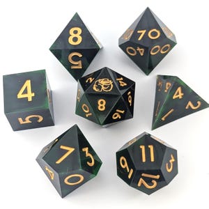 May include: Set of seven polyhedral dice in various shapes. The dice are dark green with gold-colored numbers. The dice are for tabletop games.