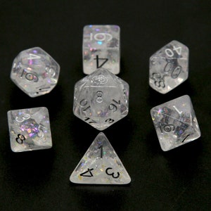 May include: Set of seven iridescent dice with black numbers. The dice are a d4, d6, d8, d10, d%, d12, and d20.