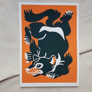 Pode incluir: Uma ilustração em preto e branco de um diabo da Tasmânia sobre um fundo laranja. O diabo é retratado em uma pose brincalhona, com a língua de fora.