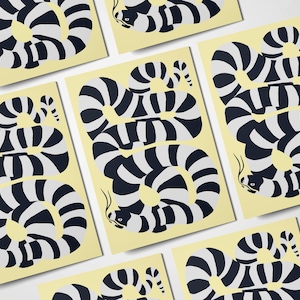 Puede incluir: Un conjunto de seis tarjetas con un diseño de rayas blancas y negras de una criatura que se asemeja a una serpiente o anguila. Las tarjetas están impresas sobre un fondo amarillo claro.