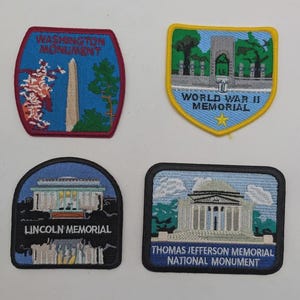 May include: Four embroidered patches featuring Washington D.C. landmarks. Top left: Washington Monument with red border. Top right: World War II Memorial with yellow border. Bottom left: Lincoln Memorial. Bottom right: Thomas Jefferson Memorial National Monument.