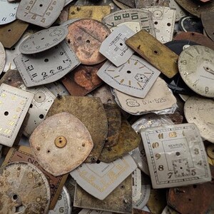 Puede incluir: Una colecci&oacute;n de esferas de reloj antiguas de diversas formas y tama&ntilde;os. Las esferas son principalmente blanquecinas, bronceadas y doradas, con n&uacute;meros negros y dorados. Algunas esferas tienen engranajes y marcas visibles, detalles de relojes antiguos.