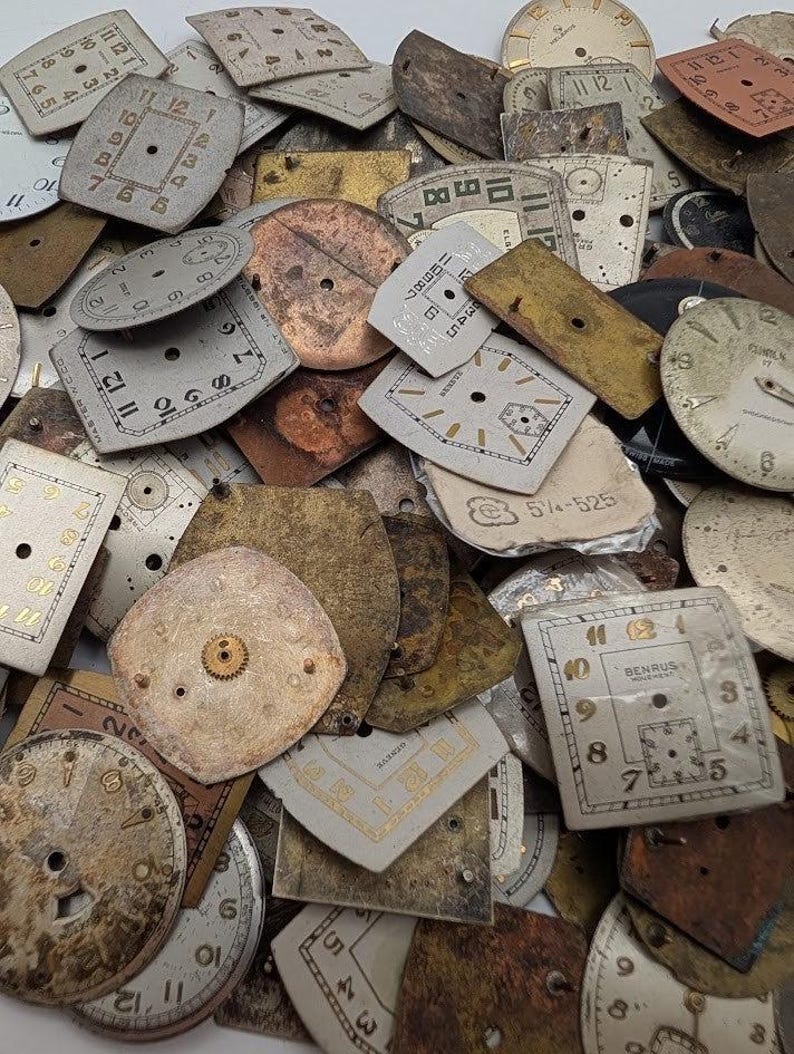 Puede incluir: Una colecci&oacute;n de esferas de reloj antiguas de diversas formas y tama&ntilde;os. Las esferas son principalmente blanquecinas, bronceadas y doradas, con n&uacute;meros negros y dorados. Algunas esferas tienen engranajes y marcas visibles, detalles de relojes antiguos.