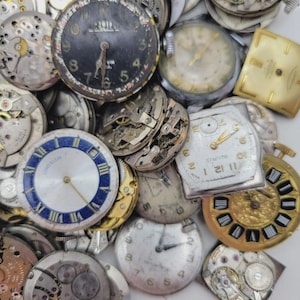 May include: A collection of vintage watch faces and watch movements. The watch faces are in various shapes and colors, including black, white, and gold. Some faces have Roman numerals, and others have Arabic numerals. The image includes the text "LORD ELGIN" and "BAURUS".