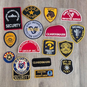 May include: A collection of various embroidered security and protection service patches in diverse shapes and colors, including rectangular, circular, and shield-style designs featuring text such as Control Security Service, Vance Uniformed, Guardsmark, Pinkerton, and City of Dallas.