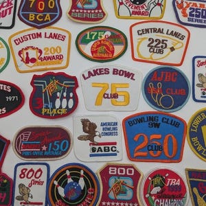May include: A collection of vintage bowling patches in various shapes and colors. Patches feature text like "800 Series", "250 Club", and "American Bowling Congress". Designs include bowling pins, eagles, and text.