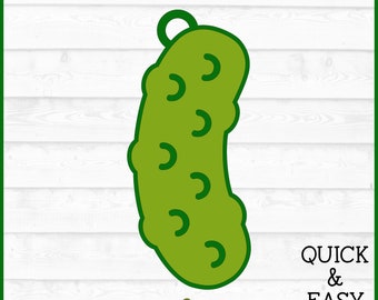 May include: A green pickle ornament with a loop for hanging. The pickle has a layered design with a series of curved lines on the surface. The text "QUICK & EASY" is visible in the lower right corner of the image.