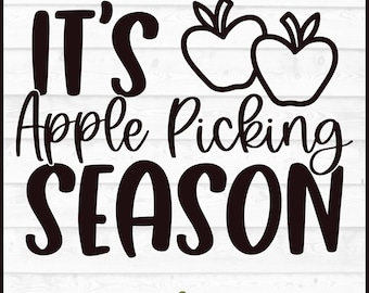 May include: Black and white graphic with the text "IT'S Apple Picking SEASON" in a bold, playful font. Two apple outlines are above the words "Apple Picking". The bottom of the graphic includes file type options: DXF, SVG, PNG, and EPS.