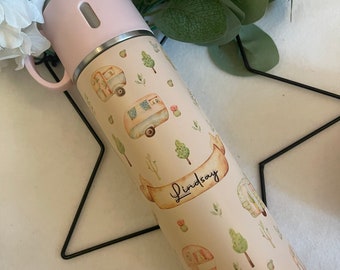 May include: A cream-colored stainless steel water bottle with a pink lid and a handle. The bottle has a watercolor design of vintage campers, trees, and cacti. The name "Lindsay" is written on a banner on the bottle.