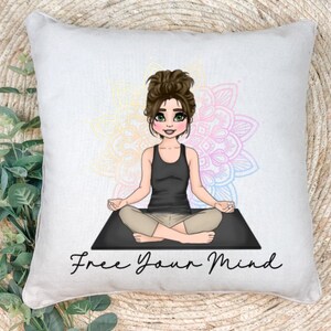 May include: A white cushion with a colourful mandala design and a cartoon illustration of a woman meditating on a black yoga mat. The text "Free Your Mind" is printed below the image.