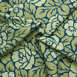 May include: A green fabric with a blue floral pattern. The fabric is folded and shows the pattern in detail.