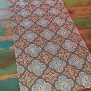 Pode incluir: Um corredor de mesa castanho com um padrão repetitivo de formas geométricas azuis, vermelhas e douradas. O corredor tem um brilho subtil e uma textura suave.