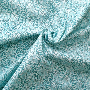 Op de afbeelding: Witte stof met een turquoiseblauw, draaiend bloemenpatroon.