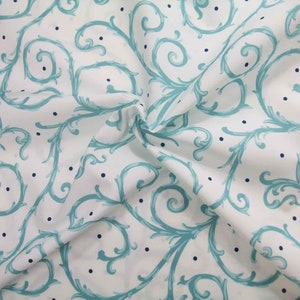 May include: White fabric with a teal blue swirling floral pattern and small white dots.