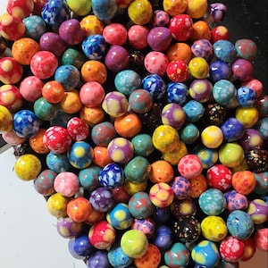 May include: A large collection of colorful ceramic mushrooms with various patterns and designs. The mushrooms are arranged in a cluster, creating a visually appealing display.