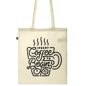 May include: A white canvas tote bag with black handles and a black graphic that says "Insert Coffee to Begin" with a stylized coffee cup and steam.