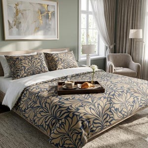 Peut inclure: Un lit avec une housse de couette à motifs floraux beiges et bleu marine et des taies d'oreiller assorties. Un plateau en bois contient une tasse de café et un croissant. Une œuvre d'art abstraite encadrée est accrochée au-dessus du lit.