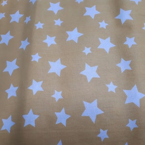 Könnte beinhalten: Senfgelber Stoff mit einem sich wiederholenden Muster aus weißen Sternen in verschiedenen Größen. Die Sterne sind gleichmäßig über dem Stoff verteilt und erzeugen ein verspieltes Design. Der Stoff scheint weich und leicht zu sein.