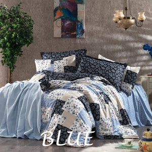 May include: A bed is made with a patchwork quilt and matching pillowcases in shades of blue, white, and navy. The quilt features floral and paisley patterns. The word "BLUE" is displayed in white text on the bedspread.