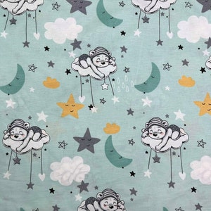 Op de afbeelding: Een lichtblauwe stof met een herhalend patroon van slapende teddyberen op wolken, sterren, manen en regendruppels. De beren dragen gestreepte hoeden en zijn omringd door verschillende stervormen in grijs, geel en wit. De wolken zijn wit en de manen zijn teal.