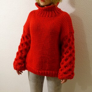 May include: A red knitted sweater with a turtleneck and textured sleeves.