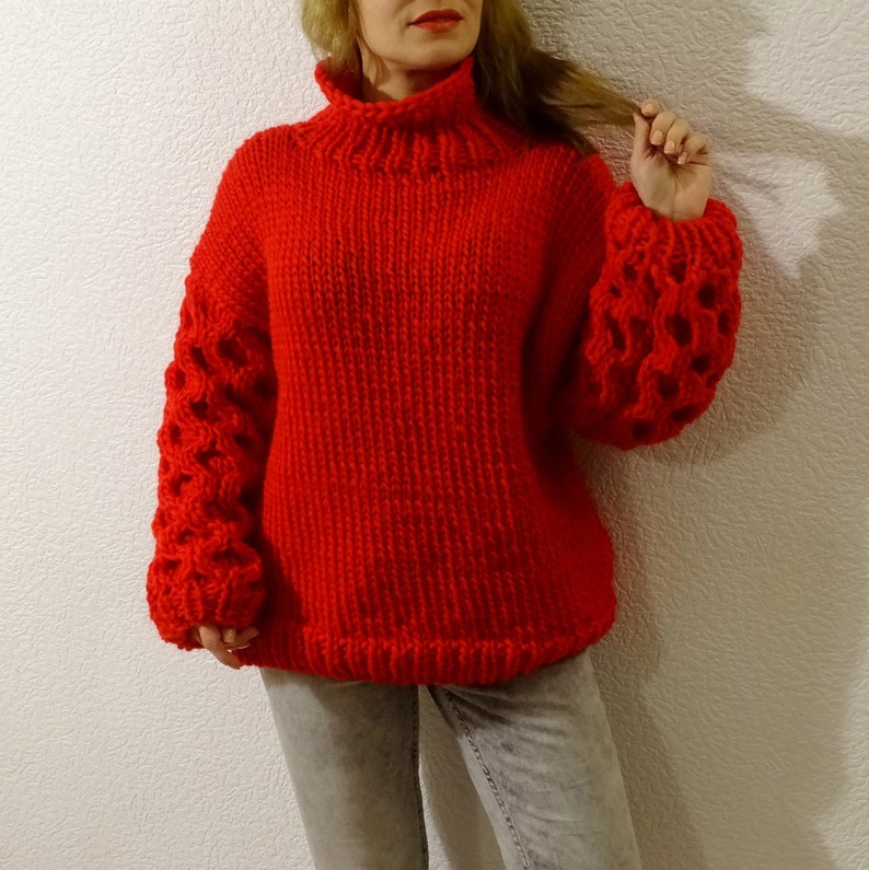 May include: A red knitted sweater with a turtleneck and large, open-weave sleeves.
