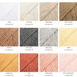May include: A collection of 12 yarn colors, including white, off-white, light beige, brown khaki, almond, dark grey, pearl grey, vanilla, goldenrod, rust, light peach, and pink marshmallow. Each color is displayed in a square with the name and uni color number listed below.