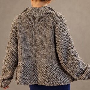 Relaxed back view of a oversized wool cardigan with substantial textured sleeves and a smooth knitted back panel.