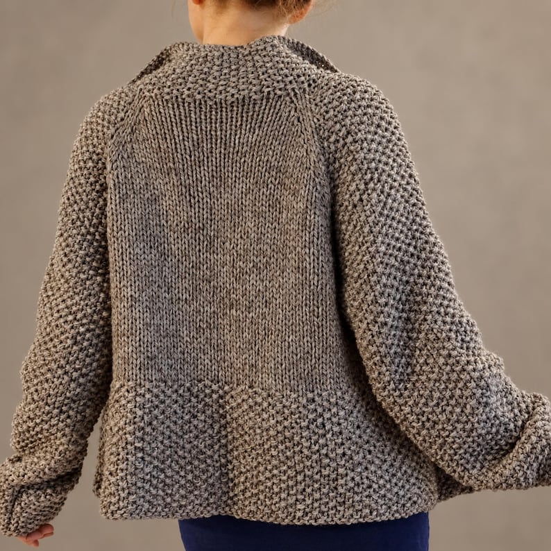 Relaxed back view of a oversized wool cardigan with substantial textured sleeves and a smooth knitted back panel.