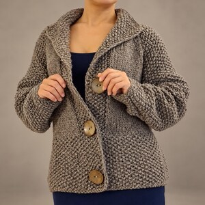 Close front view of a Ash brown wool cardigan showing its textured knit, wide collar, coconut buttons and knitted buttonholes.