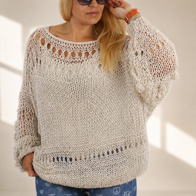 Hand knit off white cotton boho sweater with oversized fit, open knit texture and wide bell sleeves, modeled in soft natural window light.